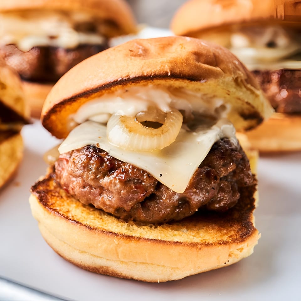 Close-up of a F. Ottomanelli burger with melted cheese and caramelized onions on a toasted bun.